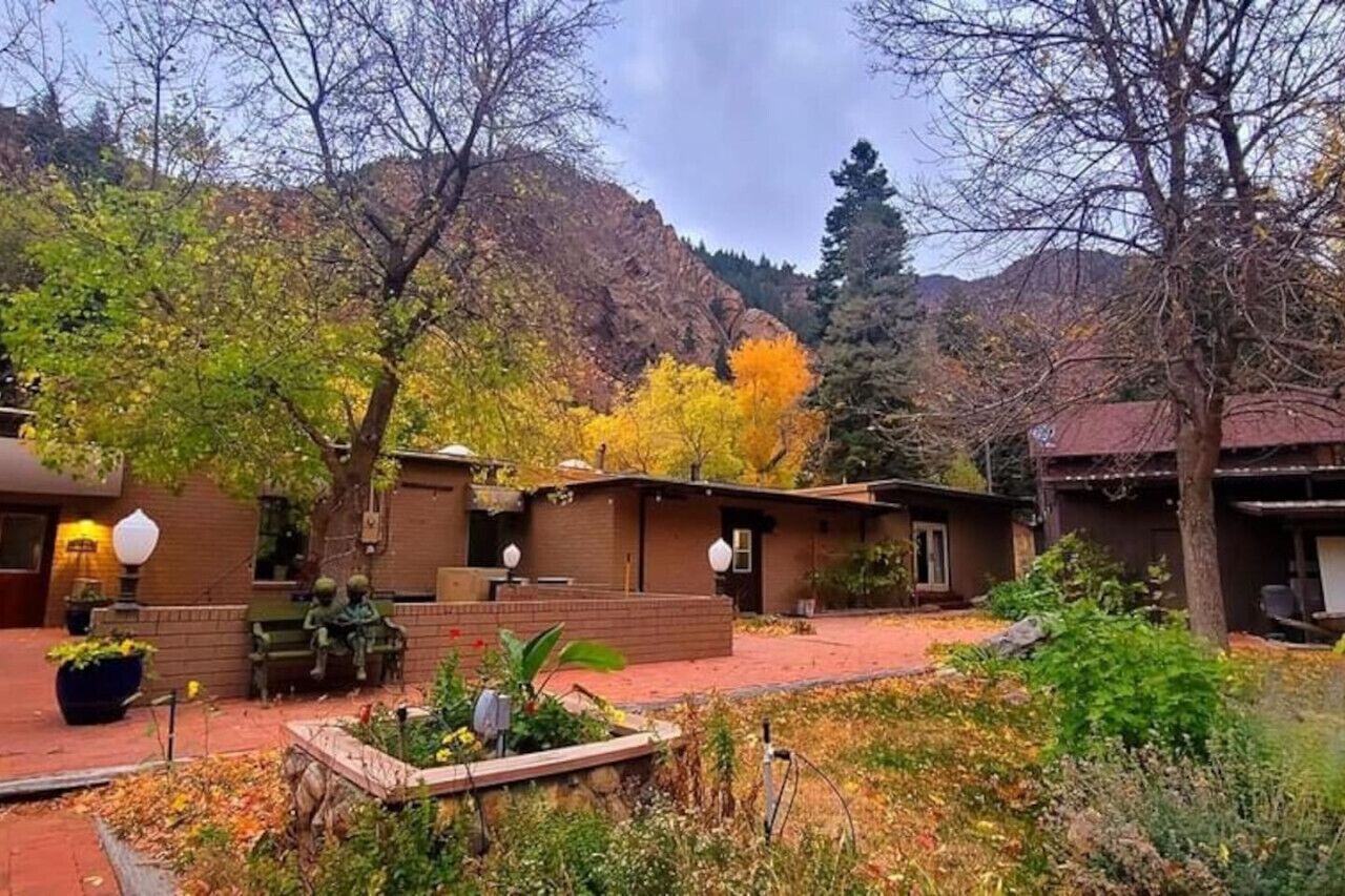 Un patio con un edificio de ladrillo, mobiliario exterior y montañas al fondo.