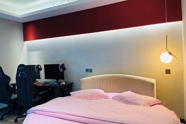 A hotel room with a bed, a desk with a computer and headphones, and gaming chairs. - Urumqi Sundan Yakaifu Theme Hotel (Urumqi)