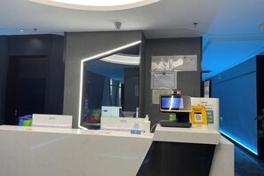 A reception area with a modern design, including a reception desk, a computer monitor, and a digital display.