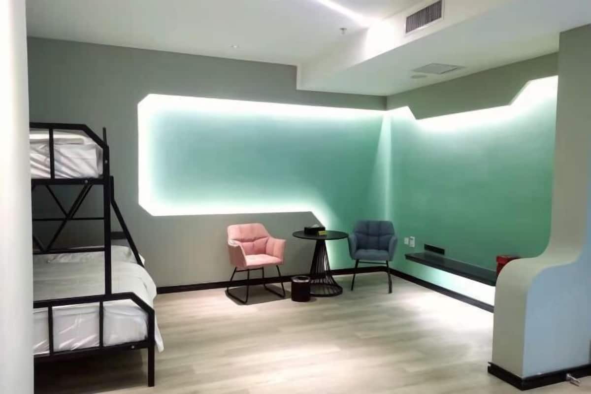 Een kamer met stapelbedden, een klein rond tafeltje, twee stoelen en een opvallend wandontwerp.
