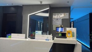 A reception desk with a modern design, a digital screen, and a QR code for check-in. - Urumqi Sundan Yakaifu Theme Hotel (Urumqi)