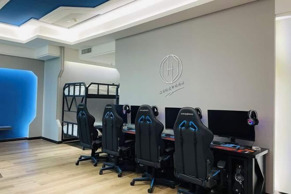 Een moderne gamekamer met vier zwarte gaming stoelen, een bureau met een computer en een monitor.