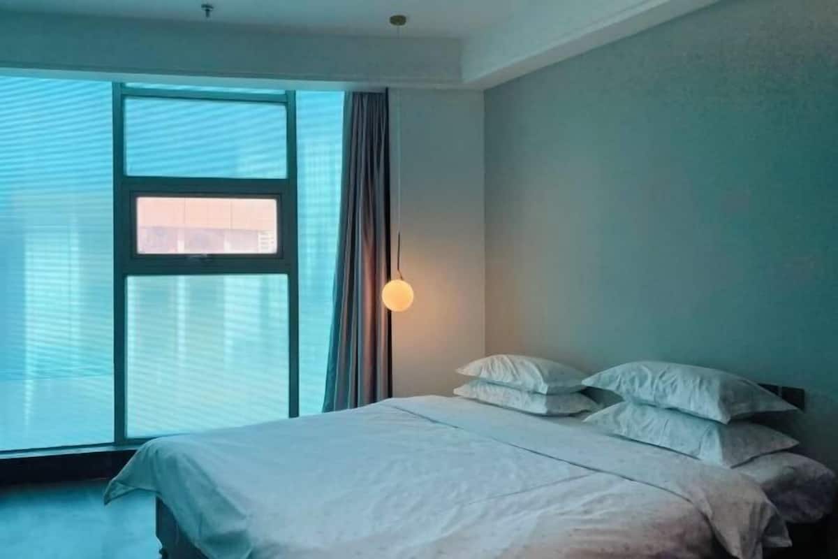 Een slaapkamer met een bed, een raam en een wandlamp.