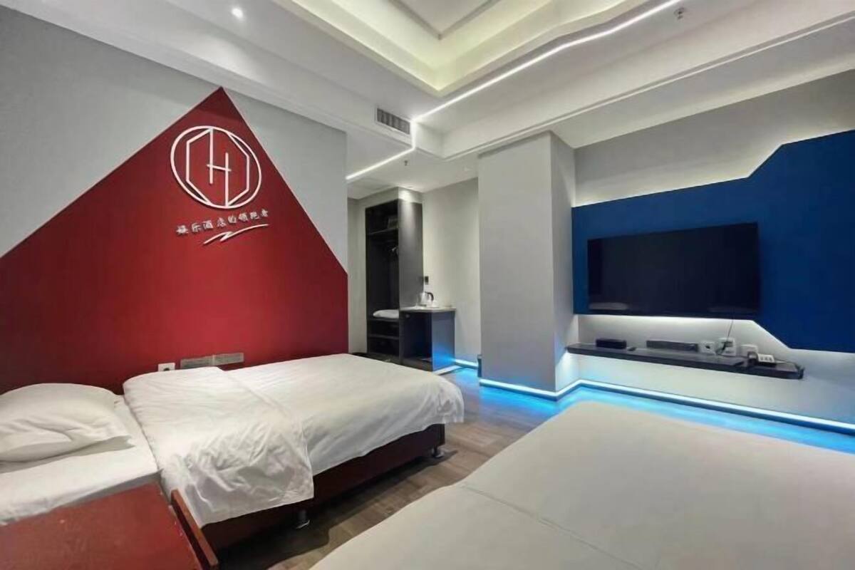 Hotelkamer met twee bedden, een televisie, een rode accentmuur en een modern design.
