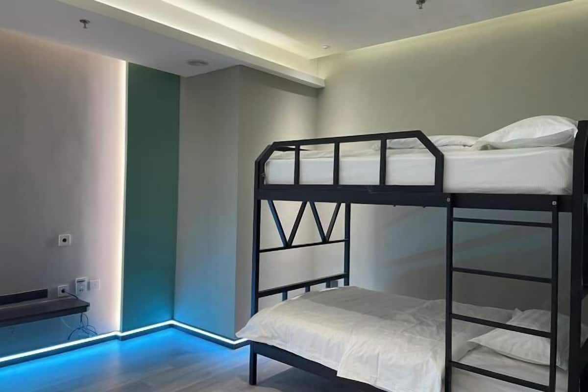 Een slaapkamer met een stapelbed, bureau en een lampje aan de muur.
