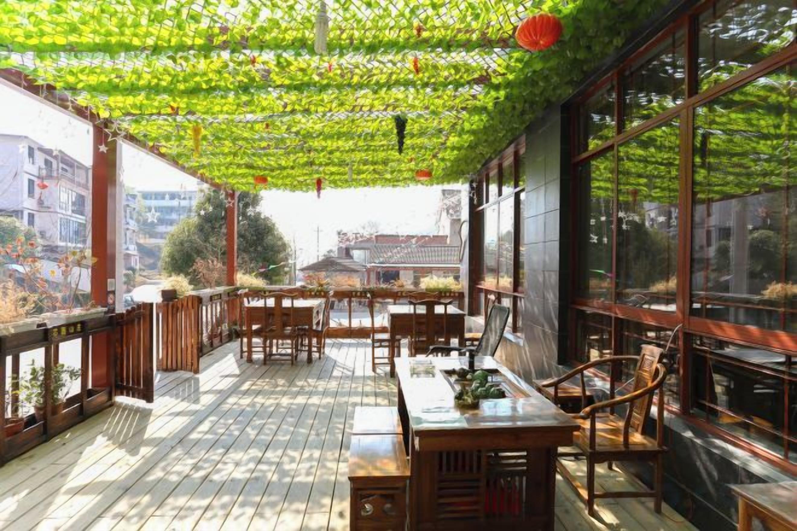 Un espace extérieur aménagé, abrité et doté de mobilier en bois et de grandes fenêtres.