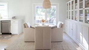 A modern kitchen with a dining area, white cabinetry, and a hanging light fixture. - Charleston House with Private Pickleball Court! (Charleston)