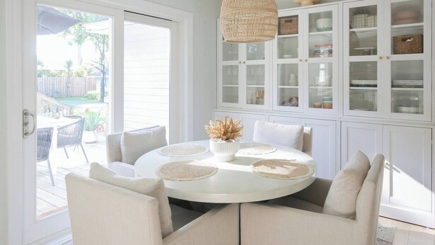 A round dining table with beige upholstered chairs, a woven placemat, and a vase with dried flowers. - Charleston House with Private Pickleball Court! (Charleston)