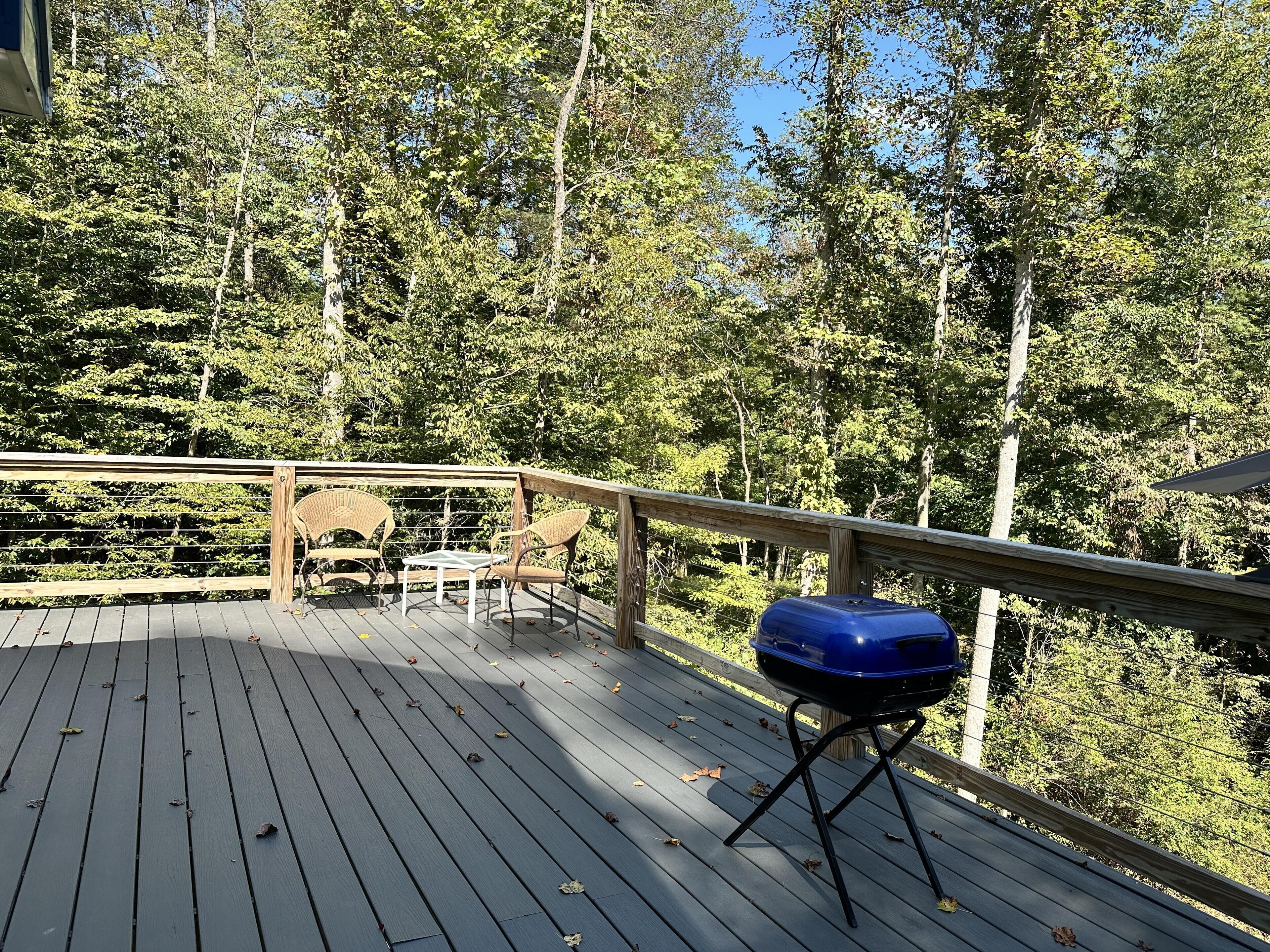 A wooden deck with a barbecue grill and wicker chairs.
