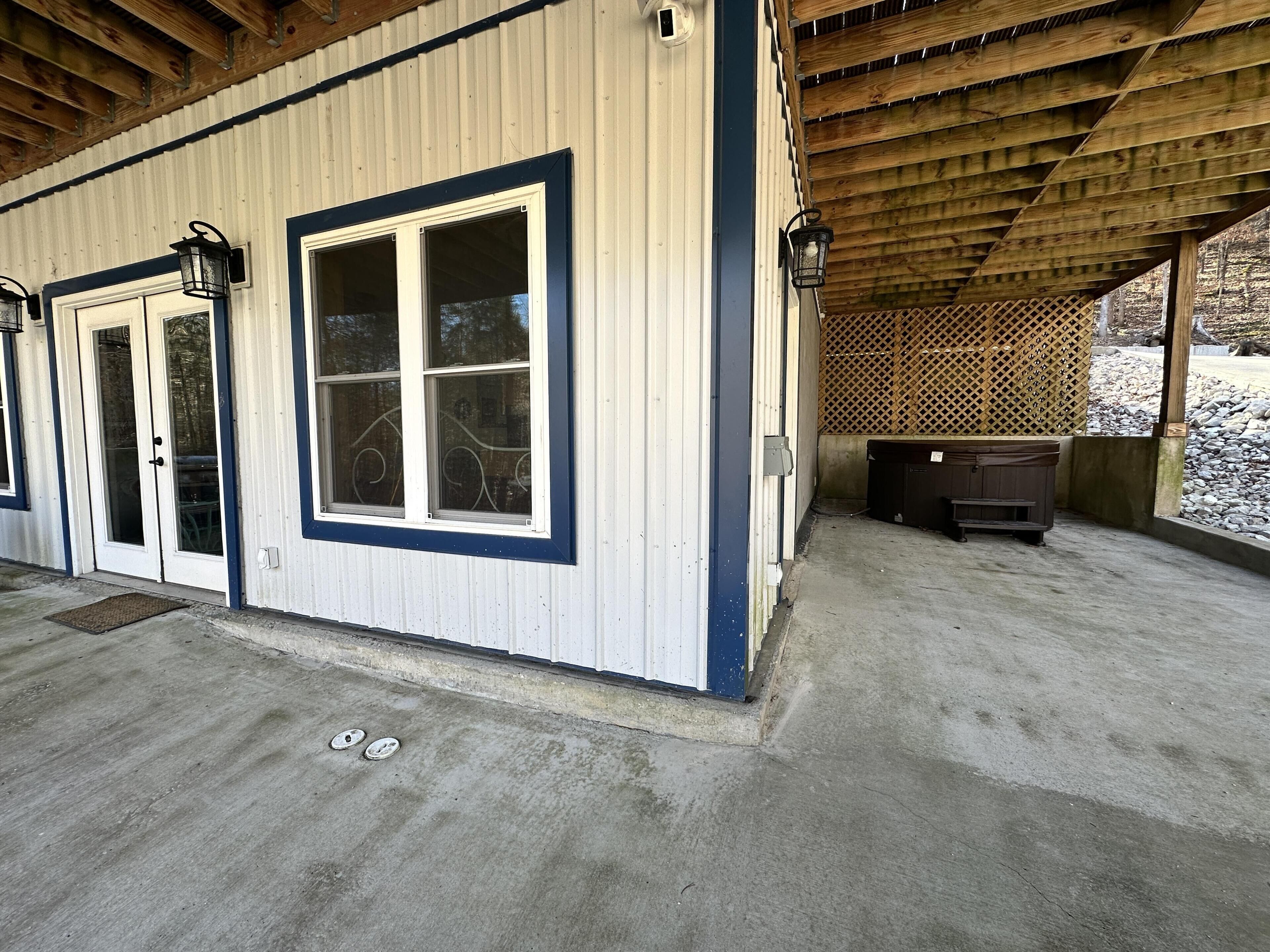 A covered outdoor area with a wooden ceiling, a concrete floor, and a large window with a metal grill.