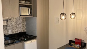 Una cocina moderna con una isla central, microondas integrado y estufa a gas. Hay luces colgantes sobre la isla.