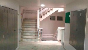 A hallway with lockers, a staircase, and a tiled floor. - Apartment Asa Norte CLN 110 ap 111 (Brasília)