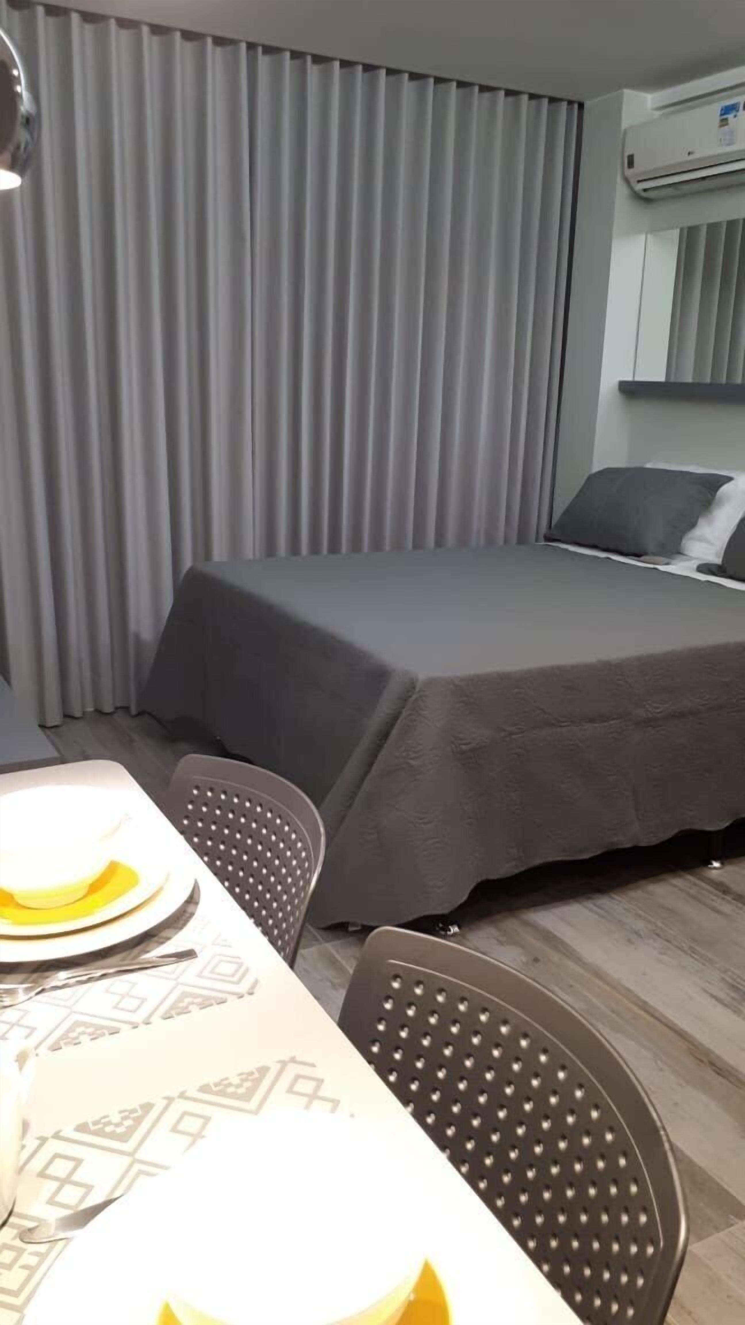 Une chambre d’hôtel comprenant un lit, une table avec des chaises et un appareil de climatisation.