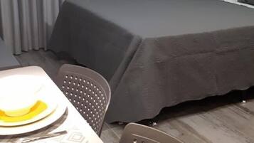 Une chambre d’hôtel comprenant un lit, une table avec des chaises et un appareil de climatisation.