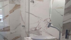 A bathroom with a marble backsplash, a white sink, and a toilet. - Apartment Asa Norte CLN 110 ap 111 (Brasília)