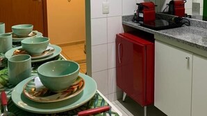 A compact kitchen with white and green cabinets, a microwave, and a red appliance on the countertop. - Loft 34m² Asa Norte CLN 213 (Brasília)