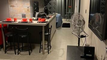 Uma cozinha moderna com uma ilha central, banquetas e uma mesa de jantar com tigelas vermelhas.