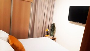 A hotel room with a bed, a nightstand, a television, and a curtain. - Apartment Asa Sul Golden Place (Brasília)