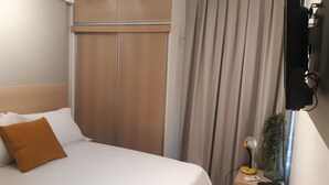 A hotel room with a bed, a nightstand, a lamp, and a TV. - Apartment Asa Sul Golden Place (Brasília)