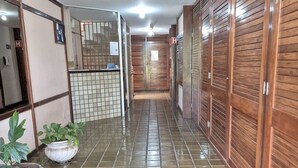 Un pasillo con suelo de baldosas, taquillas de madera y plantas en macetas.