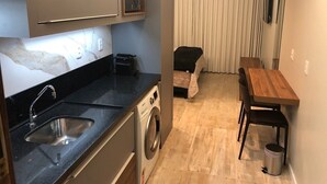 Eine kleine Küche mit Spüle, Waschmaschine und Essbereich mit Tisch und Stühlen.