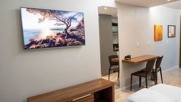 A modern room with a bed, a desk, and a chair, a painting on the wall, and a view of the sea.
