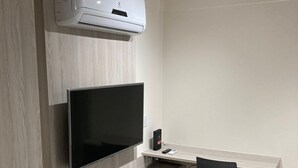 A modern kitchen with a built-in stove, a microwave, and a large flat-screen TV mounted on the wall.