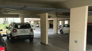 Un aparcamiento de varios niveles con columnas, donde se observan un SUV blanco y un coche plateado estacionados.