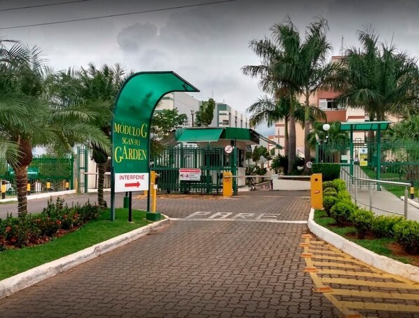 Una entrada cerrada a un área residencial, con un letrero que indica un jardín y un portero automático.