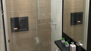 Ein modernes Badezimmer mit einer einteiligen Duschkabine, einer Toilette und einem Waschtisch mit Spiegel.