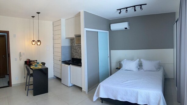 Ein kompaktes Hotelzimmer mit Bett, Küchenzeile und einer kleinen Essecke.