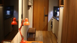 Een kleine keuken met houten kastjes, een aanrecht, een spoelbak en een magnetron.