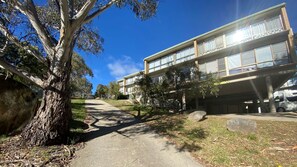 A building with a flat roof, large windows, and a paved pathway leading to it. - Alpine Mountain View 3 - Jindabyne (Jindabyne)