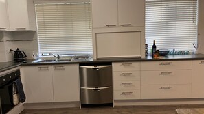A modern kitchen with white cabinetry, a stainless steel refrigerator, and a built-in oven.