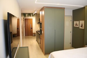 A hotel room with a bed, a wardrobe, a mirror, a sink, and a door leading to a bathroom.