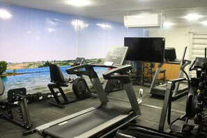 Stay active with our well-equipped gym featuring treadmills, stationary bikes, and weight machines, plus a scenic mural and TV for a motivating workout.