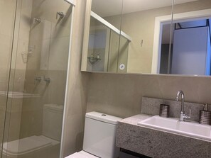 Enjoy a refreshing shower in the bathroom, featuring a glass-enclosed shower area, a toilet, and a sink with a granite countertop.
