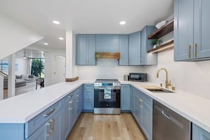 Eine moderne Küche mit blauen Schränken, einem Edelstahlbackofen und einer eingebauten Mikrowelle.