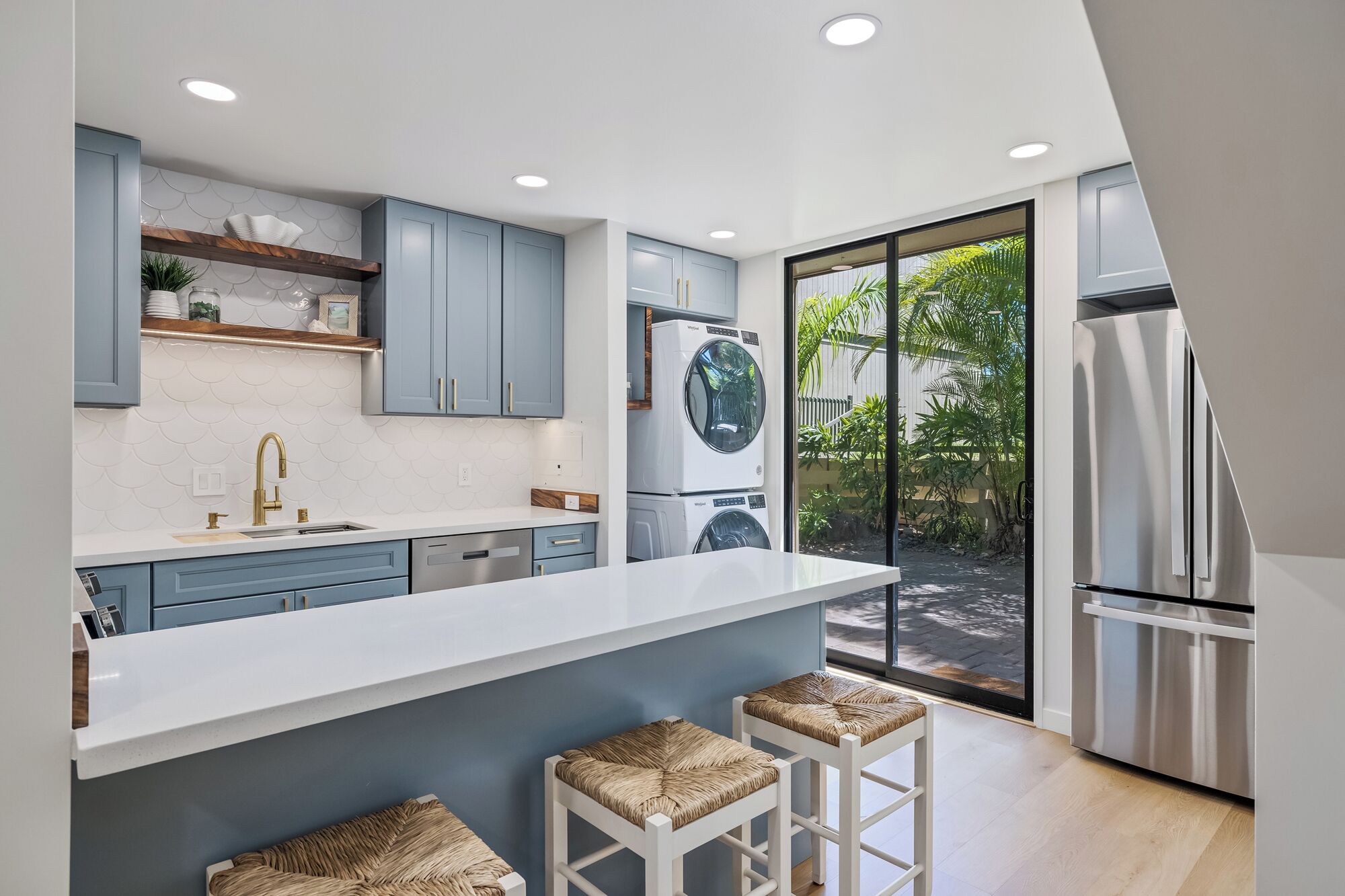 A modern kitchen with a large island, built-in appliances, and a sliding glass door to a patio.