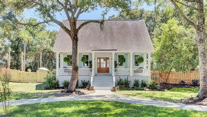 Une maison à deux étages avec un porche à l’avant, une porte en bois et un toit en briques.