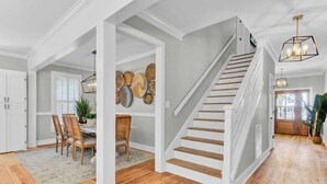 Un vaste espace de vie agrémenté d’un escalier en bois, un coin repas avec une table et des chaises, et un mur décoré de paniers tressés.
