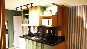 Une cuisine compacte dotée d’un plan de travail noir, de meubles en bois et d’un four à micro-ondes encastré.