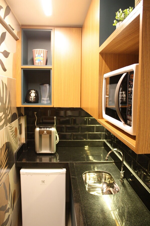 Una cocina compacta equipada con tostadora, microondas y lavamanos.