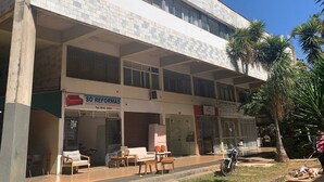 A two-story building with a sign for 'SÓ REFORMAS' and another for 'OFICINA DO SOL'.