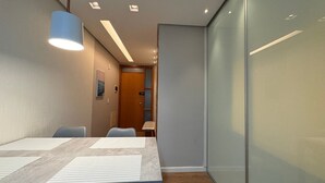 A modern conference room with a long table, chairs, and a glass partition wall. - Flat Sudoeste Ed. Leonardo (Brasília)