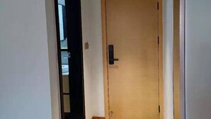 Una puerta de madera con un picaporte negro, un escalón que lleva a ella, y una pared blanca.