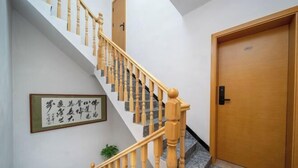 Una escalera con balaustres de madera y barandilla, que lleva a un cuarto con puerta de madera.