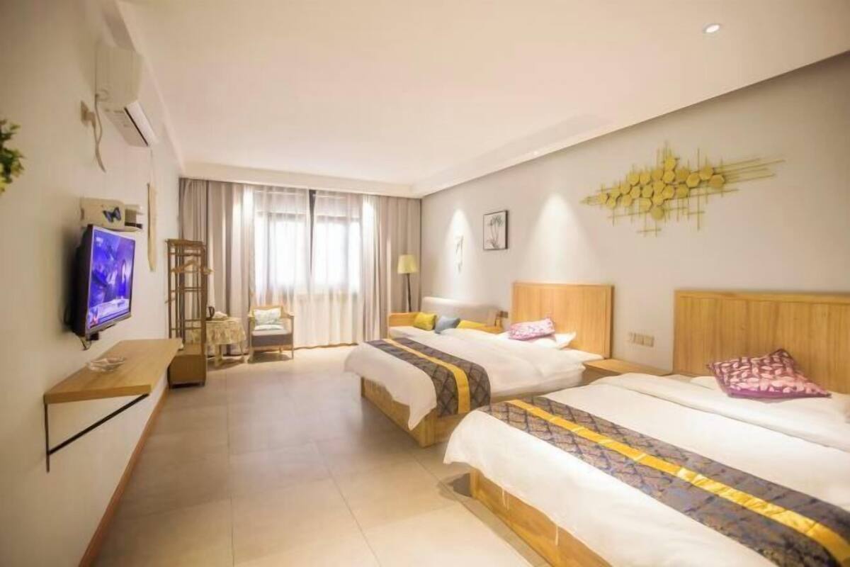 Habitación de hotel con dos camas, televisión, escritorio y ventana con cortinas.