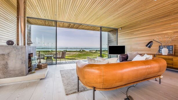 Un salon moderne avec un canapé en cuir, une cheminée et une grande fenêtre donnant sur la plage.