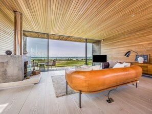 Un salon moderne avec un canapé en cuir, une cheminée et une grande fenêtre donnant sur la plage.